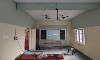 A teacher using digital content on a projector screen in a government school classroom