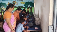 Students at computer workstations with headphones in an ICT Lab under the Karnataka Model Schools Pathways Programme, with a facilitator assisting